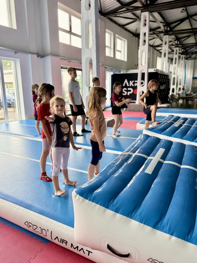 Dzieci ćwiczą przy dmuchanej ścieżce w hali Akro Spot